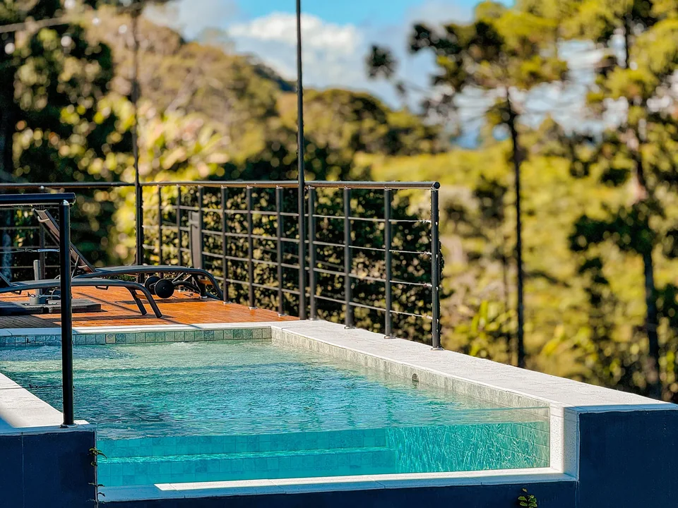 Piscina de borda infinita no deck de madeira sobre os vales da Serra da Mantiqueira