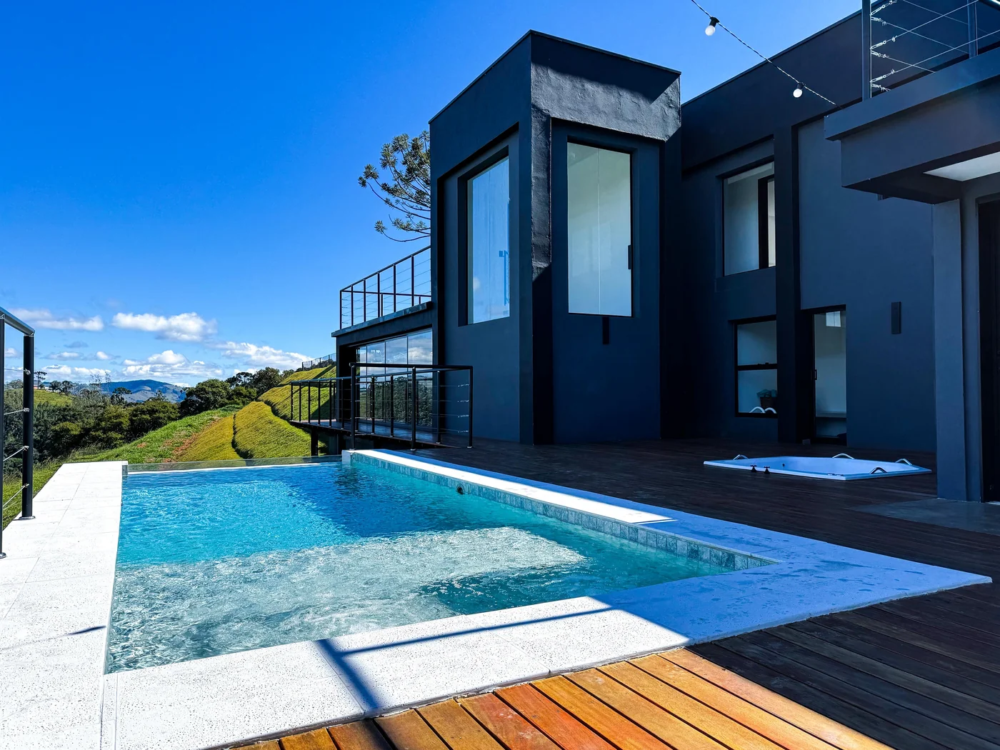 Piscina de borda infinita, arquitetura contemporânea e os vales da Serra da Mantiqueira ao fundo